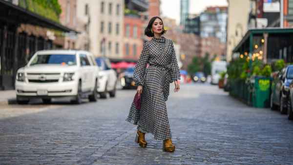 NEW YORK, NEW YORK - SEPTEMBER 12: Heart Evangelista wears golden earrings, a houndstooth pattern printed midi pleated dress, a burgundy leather bag from Carolina Herrera, golden floral print platform boots, outside Carolina Herrera, during New York Fashion Week, on September 12, 2023 in New York City. (Photo by Edward Berthelot/Getty Images)