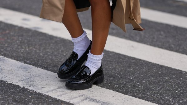 NEW YORK, NEW YORK - SEPTEMBER 15: A guest wears a beige trench coat, black patent varnished leather chunky lug-sole loafers shoes worn with white crew socks, outside Coach, during New York Fashion Week, on September 15, 2025 in New York, New York (Photo by Edward Berthelot/Getty Images)