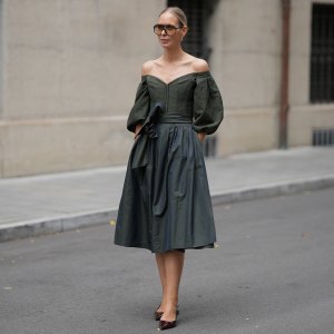 MUNICH, GERMANY - SEPTEMBER 1: Mirja Klein is seen wearing a off-the-shoulder dark green midi dress with voluminous, puffed sleeves and subtle floral texture throughout the bodice, the skirt is full and structured, cinched at the waist with a wide, matching sash tied in a bow from Cocovero; pointed-toe heels in a burgundy patent leather from Mango; oversized brown-tinted aviator sunglasses with a thin frame from Tom Ford; her blonde hair is pulled back in a sleek low bun on September 1, 2025 in Munich, Germany. (Photo by Moritz Scholz/Getty Images)