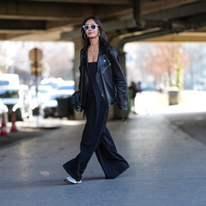 PARIS, FRANCE - MARCH 05: A guest wears white sunglasses, silver hoop earrings, shiny black oversized leather jacket, shiny black leather bag, black sleeveless flowy romper, light gray sneaker shoes, outside Stella McCartney, during the Paris Fashion week Women's Fall/Winter 2025-2026 on March 5, 2025 in Paris, France. (Photo by Edward Berthelot/Getty Images)