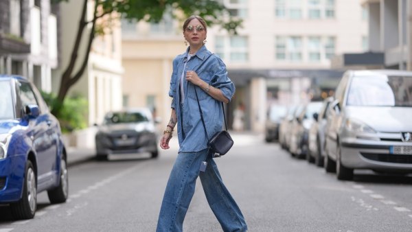 PARIS, FRANCE - JULY 17: Emy Venturini wears an oversized light blue denim shirt and wide-leg jeans, both by The Frankie Shop, layered over a white ribbed tank top by Intimissimi. Accessories include a black leather crossbody bag by Agnona, a silver Cartier wristwatch, a gold choker necklace by Vivienne Westwood, hoop earrings by Perrine Taverniti, stacked bracelets, and sunglasses by Prada. Hair is blond and styled in a center-parted low ponytail, and lips are painted with lipstick in a bold red shade, during a street style fashion photo session, on July 17, 2025 in Paris, France. (Photo by Edward Berthelot/Getty Images)