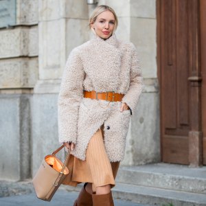 BERLIN, GERMANY - JANUARY 14: Leonie Hanne wearing total look Marc Cain: beige teddy coat, orange brown belt, pleated skirt, brown boots and bucket bag seen during the Berlin Fashion Week Autumn/Winter 2020 on January 14, 2020 in Berlin, Germany. (Photo by Christian Vierig/Getty Images)