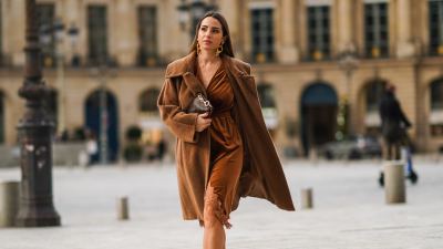 Maria Rosaria Rizzo wears golden long earrings from Raspini, a brown fluffy long winter coat from Max Mara, a brown leather monogram Vuitton bag, a brown velvet low-neck v-neck dress with lace and floral embroidery on the bottom part from Imprevu, brown high heeled shoes from Michael Kors, on December 04, 2020 in Paris, France.