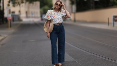 Aline Kaplan wearing Baum & Pferdgarten wide leg blue denim pants, & other stories white flower pattern cropped blouse and orange summer heels and Mango orange black shades on June 06, 2023 in Berlin, Germany.