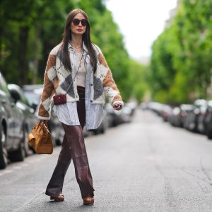 PARIS, FRANCE - APRIL 27: Heart Evangelista wears sunglasses, a golden necklace, a gray brown and white wool cardigan with checked patterns, a white t-shirt from Saint-Laurent YSL, a belt, burgundy slit leather pants , a burgundy leather mini quilted Chanel bag, an orange / brown large Hermes bag, brown shoes, during a street style fashion photo session, on April 27, 2024 in Paris, France. (Photo by Edward Berthelot/Getty Images)
