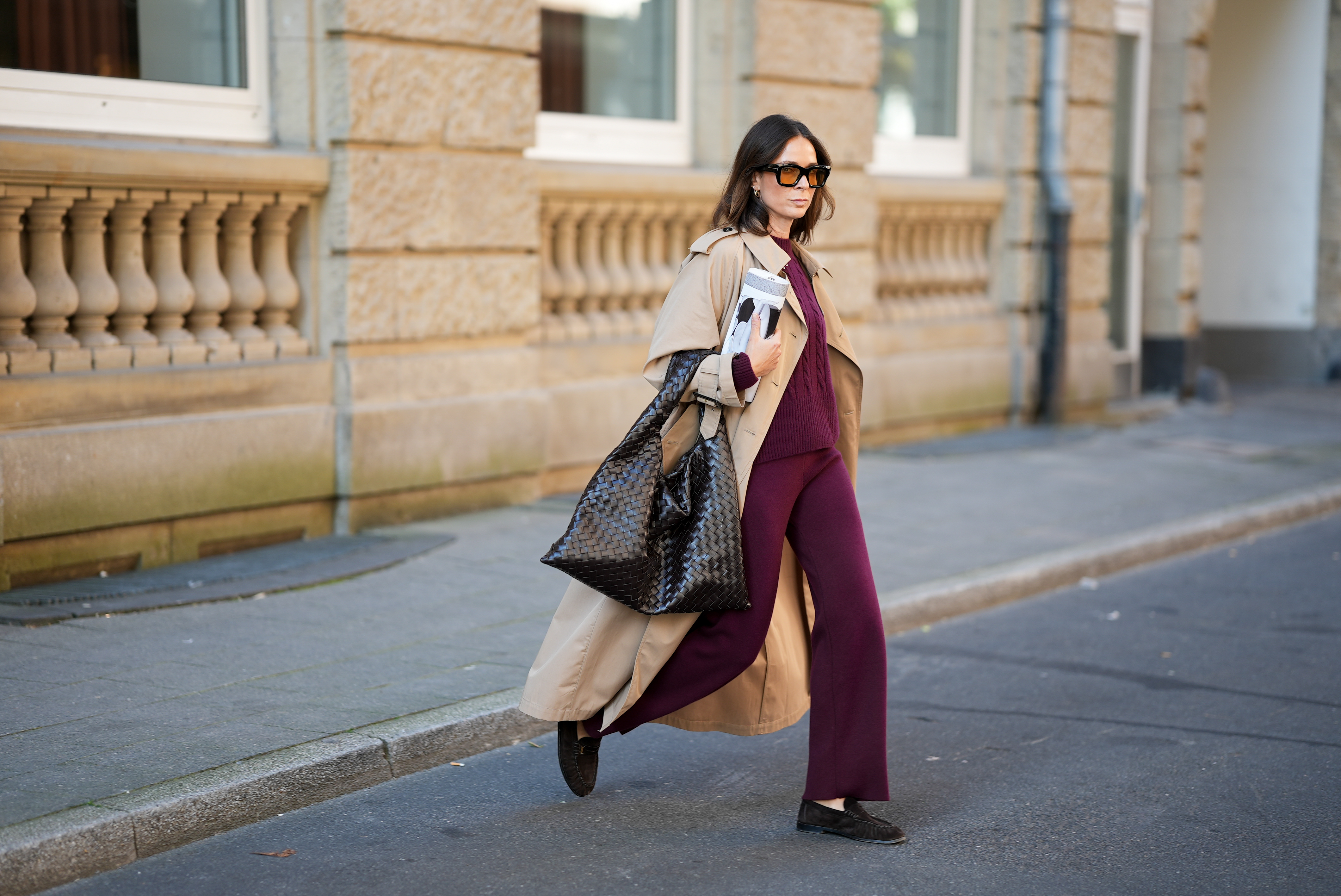 DUESSELDORF, GERMANY - AUGUST 19: Patricia Wirschke is seen wearing a classic beige long Herno trench coat, with a notched collar, storm flap, and belted cuffs; a burgundy Incentive co ord set with a cable-knit sweater, featuring a ribbed hem, cuffs, and neckline and wide-leg knit pants with a relaxed fit; a pair of Le Loafer soft suede Saint Laurent moccasins in dark brown with golden logo detail on the side; a dark brown Hop bag from Bottega Veneta with the famous Intrecciato leather construction, woven; Tom Ford Ilias squared frame black sunglasses with orange toned lens; Bvlgari Serpenti Viper golden earrings; her brown hair is styled in a straight, shoulder-length look with a middle part; she holds a rolled up magazine in her hand on August 19, 2025 in Duesseldorf, Germany. (Photo by Moritz Scholz/Getty Images)