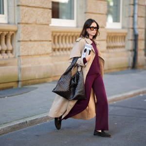 DUESSELDORF, GERMANY - AUGUST 19: Patricia Wirschke is seen wearing a classic beige long Herno trench coat, with a notched collar, storm flap, and belted cuffs; a burgundy Incentive co ord set with a cable-knit sweater, featuring a ribbed hem, cuffs, and neckline and wide-leg knit pants with a relaxed fit; a pair of Le Loafer soft suede Saint Laurent moccasins in dark brown with golden logo detail on the side; a dark brown Hop bag from Bottega Veneta with the famous Intrecciato leather construction, woven; Tom Ford Ilias squared frame black sunglasses with orange toned lens; Bvlgari Serpenti Viper golden earrings; her brown hair is styled in a straight, shoulder-length look with a middle part; she holds a rolled up magazine in her hand on August 19, 2025 in Duesseldorf, Germany. (Photo by Moritz Scholz/Getty Images)