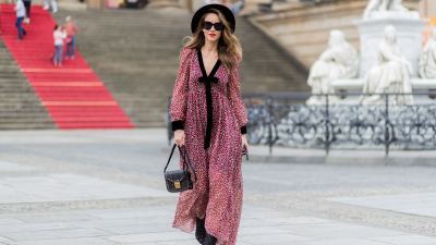 Alexandra Lapp wearing Boho Style, a red and cream floral print maxi dress from Philosophy di Lorenzo Serafini in sheer silk chiffon and bold black trims with a ribbon tie, Toubootfrou ankle boots with rete, organze and suede in black from Christian Louboutin, Celine Audrey sunglasses in black, Maison Maison Michel hat Virginie fedora, MCM Patricia Shoulder Bag in a vintage shape during the Mercedes-Benz Fashion Week Berlin Spring/Summer 2018 on July 7, 2017 in Berlin, Germany.