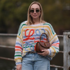 BERLIN, GERMANY - OCTOBER 25: Sonia Lyson seen wearing Celine gold Triomphe oval shaped sunglasses, silver earrings, Loewe colorful striped wool knit sweater, Hermès Kelly brown leather belt, Zara light blue wide leg denim / jeans pants, Gucci brown leather Bamboo bag, on October 25, 2023 in Berlin, Germany. (Photo by Jeremy Moeller/Getty Images)
