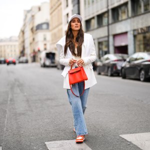 PARIS, FRANCE - APRIL 30: Tamara Kalinic wears a white Celine cap, a white latte ribs tank top, a gold chain pendant necklace, a white long Saint Laurent YSL blazer jacket, a white embroidered Chanel sweater, a red shiny leather Kelly Hermes handbag, blue faded denim boyfriend jeans Margiela pants, red and white shiny leather Nike Air Force 1 sneakers, on April 30, 2021 in Paris, France. (Photo by Edward Berthelot/Getty Images)