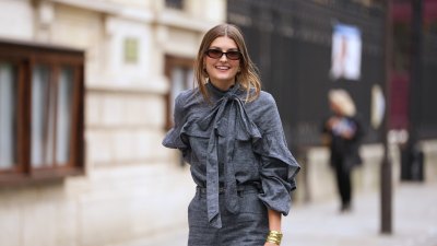 PARIS, FRANCE - OCTOBER 06: A guest wears black square sunglasses, a gray blue denim ruffled high neck / knot bow tie / long sleeves blouse, matching gray blue flared suit pants, outside Zimmermann, during Paris Fashion Week - Womenswear Spring Summer 2026, on October 06, 2025 in Paris, France (Photo by Edward Berthelot/Getty Images)