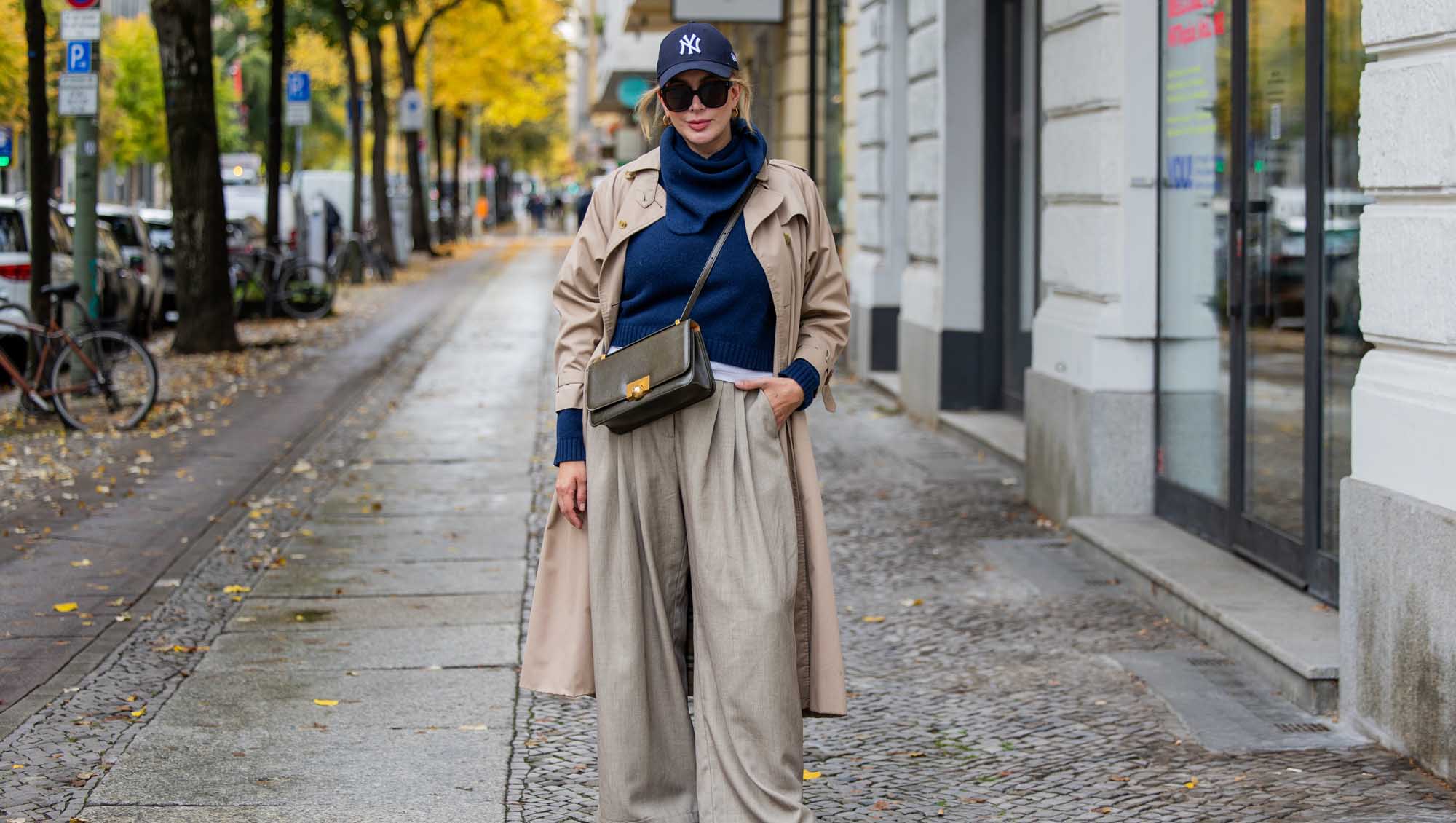 A woman walking in the cirt wearing Fall Trousers and a long jacket.