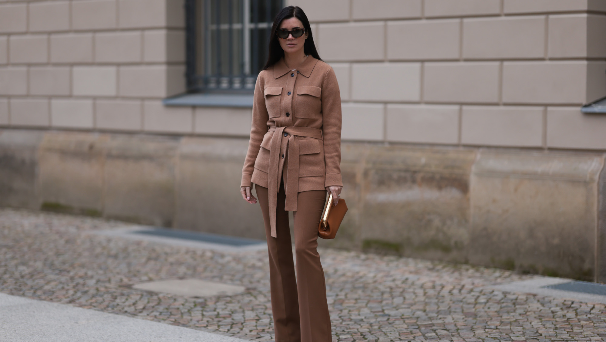 Leo Eberlin seen wearing YSL brown tortoise sunglasses, Leo Mathild diamond jewelry, Allude x Leo Mathild brown cashmere wool cardigan jacket, Zara brown suit pants, Fendi brown leather clutch / pouch bag and Christian Louboutin brown leather heels / pumps, on February 25, 2024 in Berlin, Germany.
