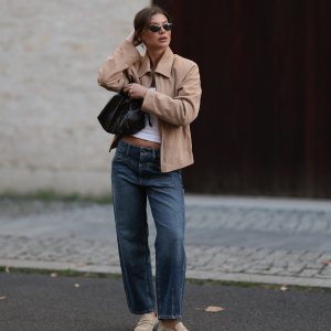 BERLIN, GERMANY - SEPTEMBER 06: Sophia Geiss seen wearing Vehla Eyewear narrow oval-shaped black sunglasses with sleek frames, crisp white scoop-neck cotton basic tank top, The Worn cropped beige suede vintage jacket with a structured collar and relaxed sleeves, Cambio straight-leg mid-wash slightly loose denim jeans, The Frankie Shop black small leather drawstring bag with a glossy finish and Camper beige suede leather loafers, on September 06, 2025 in Berlin, Germany. (Photo by Jeremy Moeller/Getty Images)
