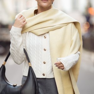 PARIS, FRANCE - MARCH 06: Gili Biegun wears grey pants, white knitted top with long sleeves, and pale yellow long wide scarf, balck leather bag during the Womenswear Fall/Winter 2025/2026 as part of Paris Fashion Week on March 06, 2025 in Paris, France. (Photo by Raimonda Kulikauskiene/Getty Images)