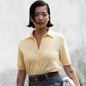 MILAN, ITALY - SEPTEMBER 25: A guest wears a polo styled light yellow short sleeved cardigan, a brown leather belt, a white leather bag and a grey mini skirt outside Prada show during the Milan Fashion Week Womenswear Spring/Summer 2026 on September 25, 2025 in Milan, Italy. (Photo by Valentina Frugiuele/Getty Images)