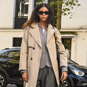 PARIS, FRANCE - OCTOBER 05: Model Nazarit Machin is seen wearing a tan trench coat, gray cardigan, gray pants, shoes and black sunglasses with black bag outside the Lacoste show during the Womenswear Spring Summer 2026 as part of Paris Fashion Week on October 05, 2025 in Paris, France. (Photo by Daniel Zuchnik/Getty Images)