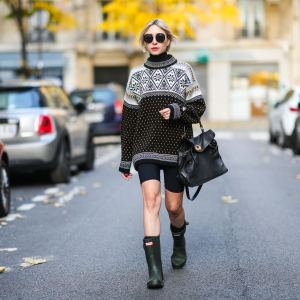 PARIS, FRANCE - NOVEMBER 18: Emy Venturini wears black sunglasses from Linda Farrow & The Row, a white with black and yellow print pattern wool turtleneck vintage pullover, black cyclist shorts from Alesia Concept, a black shiny grained leather handbag, khaki ankle rain boots from Hunter, during a street style fashion photo session, on November 18, 2021 in Paris, France. (Photo by Edward Berthelot/Getty Images)