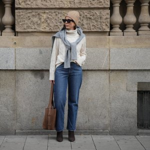 DUESSELDORF, GERMANY - NOVEMBER 10: Patricia Wirschke is seen wearing a cream cable-knit turtleneck sweater by Tommy Hilfiger; a light grey cable-knit sweater draped over her shoulders by Tommy Hilfiger; straight-leg blue jeans by Levi’s; brown suede boots with a pointed toe by Massimo Dutti; a brown suede tote bag with a shoulder strap by Max Mara; black cat-eye sunglasses by Phoebe Philo; a beige ribbed beanie with an embroidered crest logo by Tommy Hilfiger; her brown hair is worn straight and tucked into the collar; gold “Serpenti” earrings by Bulgari on November 10, 2025 in Duesseldorf, Germany. (Photo by Moritz Scholz/Getty Images)