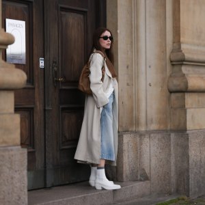 COPENHAGEN, DENMARK - AUGUST 10: Annabel Rosendahl seen wearing black sunglasses, white shirt, beige long coat, light blue denim skirt, brown leather bag and Copenhagen StudiosCPH236 Nappa White leather boots, on August 10, 2023 in Copenhagen, Denmark. (Photo by Jeremy Moeller/Getty Images for The Wants Social / Copenhagen Studios)