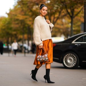 PARIS, FRANCE - SEPTEMBER 28: Tamara Kalinic wears a wool pullover, an orange shiny silky skirt, earrings, a Fendi bag, black high heeled boots, outside CDG Comme des Garçons, during Paris Fashion Week - Womenswear Spring Summer 2020 on September 28, 2019 in Paris, France. (Photo by Edward Berthelot/Getty Images)