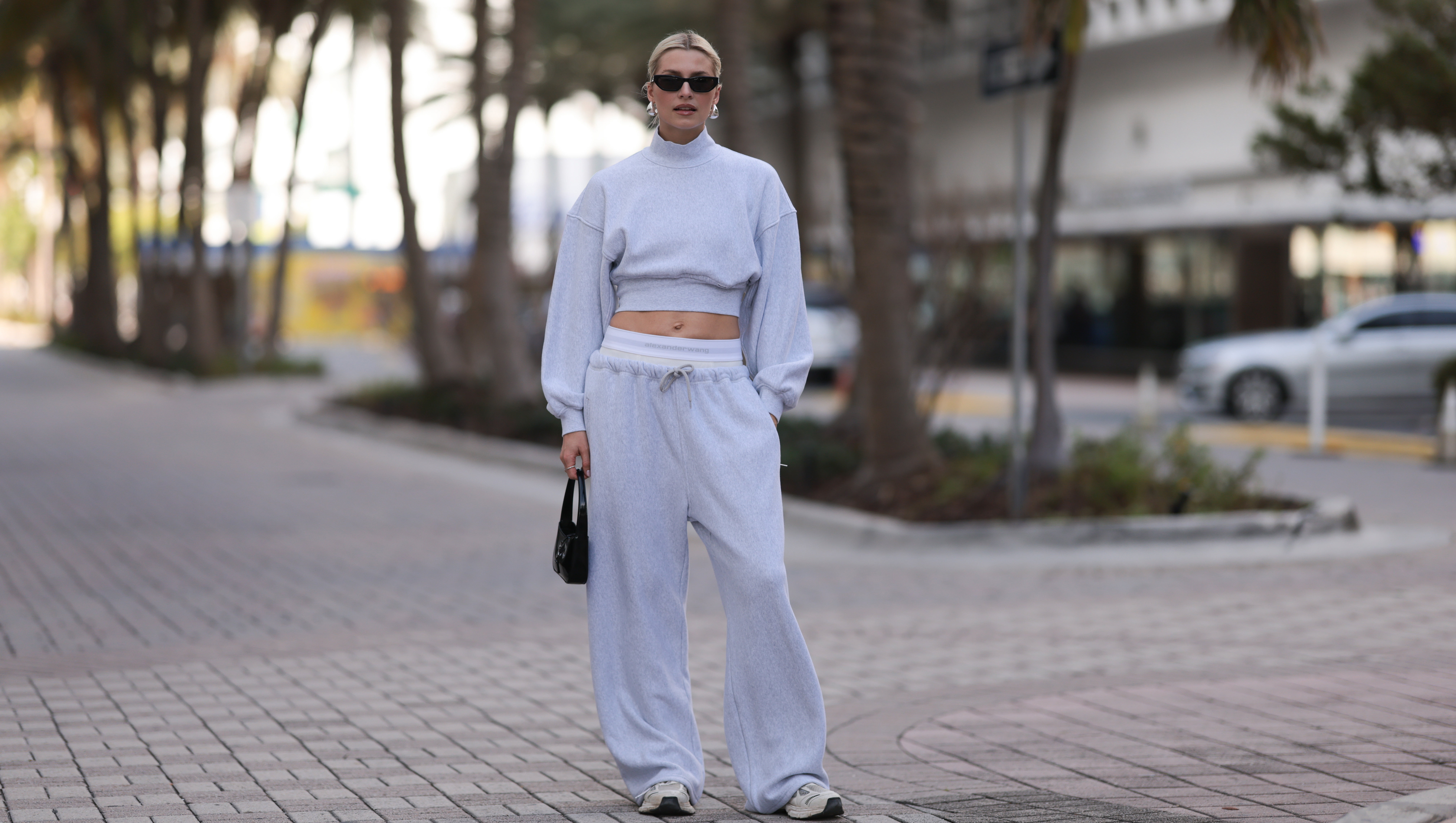 MIAMI, FLORIDA - DECEMBER 08: Lena Gercke seen wearing Saint Laurent black sunglasses, silver statement necklace, Alexander Wang light grey high neck cotton cropped jumper / sweater, Alexander Wang light grey cotton wide leg jogger pants with underwear detail, Saint Laurent black varnishes leather mini bag and Axel Arigato white leather sneakers, on December 08, 2023 in Miami, Florida. (Photo by Jeremy Moeller/Getty Images)2