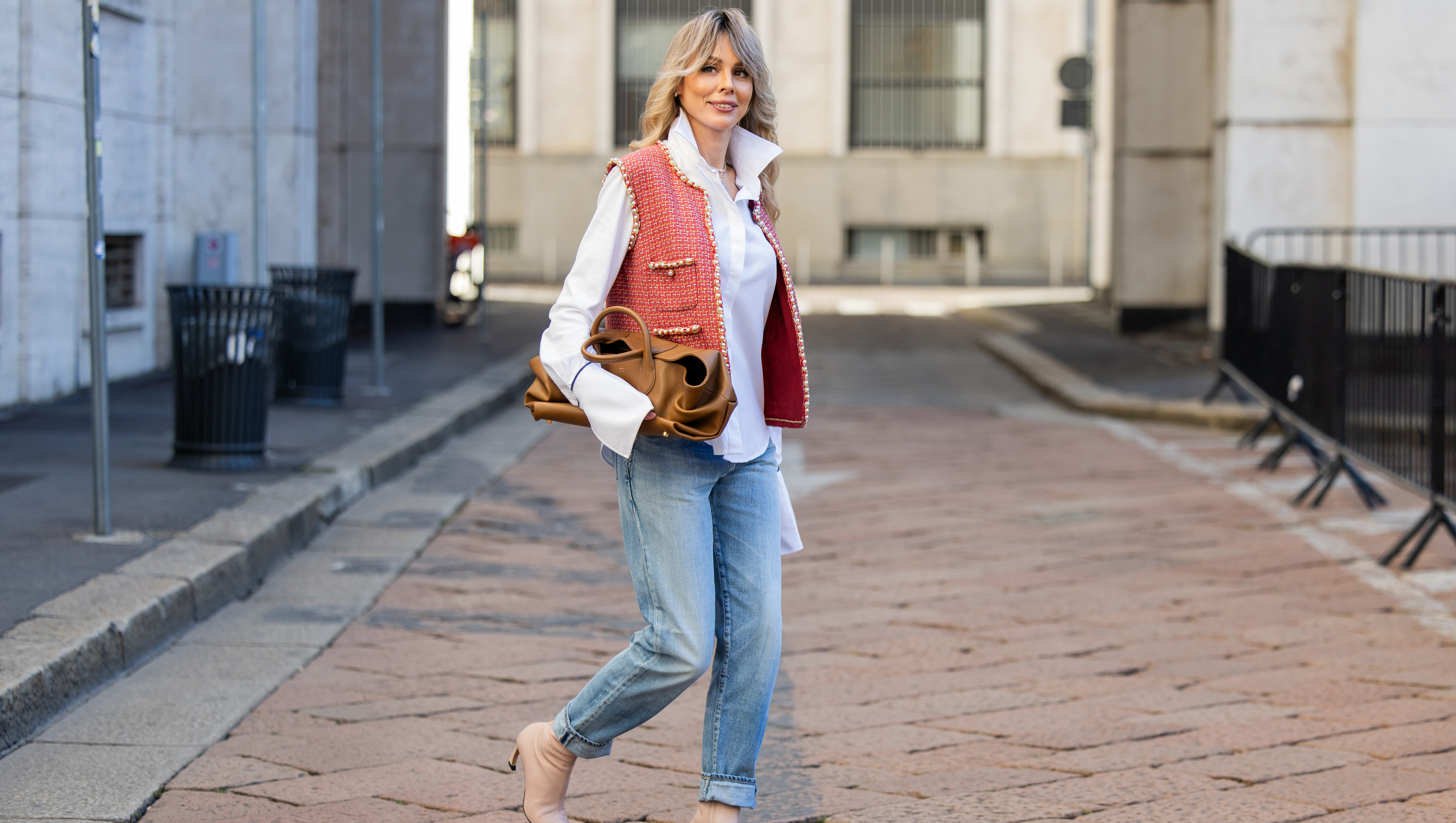 MILAN, ITALY - SEPTEMBER 28: Ekaterina Mamaeva wears white shirt Anna Quan, red vest Chanel, jeans Saint Laurent, rose ankle boots Acne Studios, brown bag Khaite during the Milan Fashion Week Womenswear Spring/Summer 2026 on September 28, 2025 in Milan, Italy. (Photo by Christian Vierig/Getty Images)