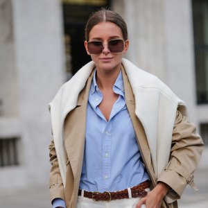 PARIS, FRANCE - APRIL 21: Diane Batoukina wears dark brown squared sunglasses from Dior, a pale blue cotton shirt from Ralph Lauren, a white matte large cashmere pullover from Weekend & Beyond, a beige oversized long trench coat from Filippa K, a brown braided leather belt from Ralph Lauren, white linen large pants from Ralph Lauren, a camel brown shiny leather crocodile print pattern handbag from Ralph Lauren, during a street style fashion photo session, on April 21, 2023 in Paris, France. (Photo by Edward Berthelot/Getty Images)
