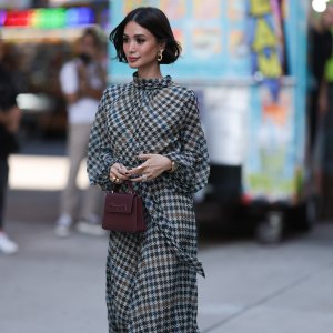 NEW YORK, NEW YORK - SEPTEMBER 12: Heart Evangelista is seen wearing golden earrings, a white/black/brown houndstooth patterned nigh neck midi dress with puffy long-sleeves, a golden watch, several rings in silver and gold, a purple leather bag from Carolina Herrera and plateau ankle boots in golden suede with floral print and chunky silber heels outside before the Carolina Herrera Spring Summer 2024 Runway Show on September 12, 2023 in New York City. (Photo by Jeremy Moeller/Getty Images)