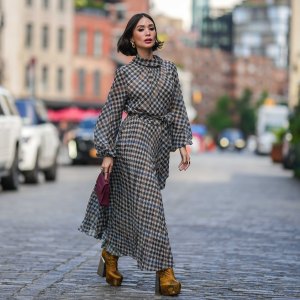 NEW YORK, NEW YORK - SEPTEMBER 12: Heart Evangelista wears golden earrings, a houndstooth pattern printed midi pleated dress, a burgundy leather bag from Carolina Herrera, golden floral print platform boots, outside Carolina Herrera, during New York Fashion Week, on September 12, 2023 in New York City. (Photo by Edward Berthelot/Getty Images)