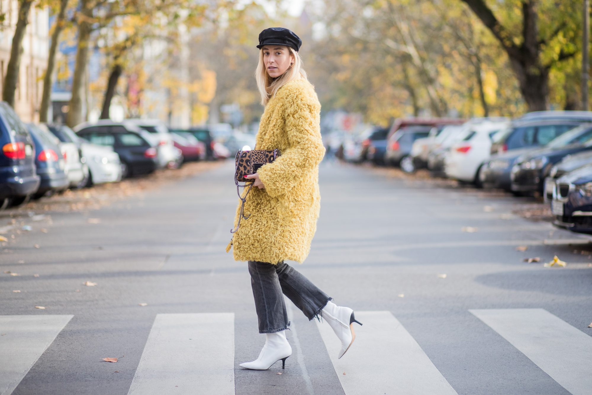 BERLIN, GERMANY - NOVEMBER 04: Sonia Lyson Jimmy Choo lockett petite bag hazelnut mix with leopard pony mix, shearling mustard coat Longchamp, black turtleneck & black Zara hat, dark grey skinny cropped flared jeans Citizens of Humanity, white H&M boots on November 4, 2017 in Berlin, Germany. (Photo by Christian Vierig/Getty Images)