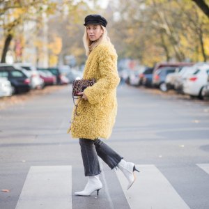 BERLIN, GERMANY - NOVEMBER 04: Sonia Lyson Jimmy Choo lockett petite bag hazelnut mix with leopard pony mix, shearling mustard coat Longchamp, black turtleneck & black Zara hat, dark grey skinny cropped flared jeans Citizens of Humanity, white H&M boots on November 4, 2017 in Berlin, Germany. (Photo by Christian Vierig/Getty Images)