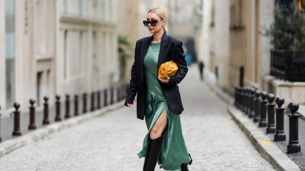 PARIS, FRANCE - JANUARY 25: Justyna Czernia wears sunglasses, gold earrings, a green mint satin silk slit / split long dress, a black oversized blazer jacket, an orange shiny leather puffy handbag from Bottega Veneta, black shiny leather pointed high boots, gold ring, outside Alexis Mabille, during Paris Fashion Week - Haute Couture Spring/Summer 2022, on January 25, 2022 in Paris, France. (Photo by Edward Berthelot/Getty Images)