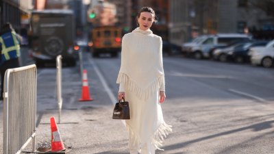 NEW YORK, NEW YORK - FEBRUARY 14: Mary Leest wears gold earrings, a white ribbed wool high neck fringed cloak, a matching white fringed wool skirt, a dark brown shiny leather crocodile print pattern handbag, silver rings outside the Bevza show , during New York Fashion Week, on February 14, 2022 in New York City. (Photo by Jeremy Moeller/Getty Images)
