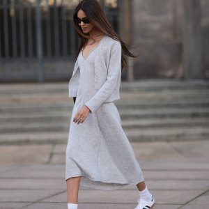 Jill Asemota seen wearing black vintage sunglasses, Dorothee Schumacher grey wool knit long dress, matching Dorothee Schumacher grey wool knit cardigan jacket, white cotton socks, Adidas white leather Samba sneakers, on November 04, 2023 in Berlin, Germany.