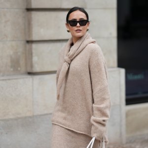 HAMBURG, GERMANY - OCTOBER 16: Laura Noltemeyer is seen wearing an oversized beige alpaca wool sweater with tie-back detailing by Aylin König; a long alpaca wool knit skirt in a straight cut by Aylin König; an alpaca knit scarf draped and knotted around the neck by Aylin König; a white intrecciato leather handbag called „Arco Bag“ by Bottega Veneta; slim black cat-eye sunglasses by Yves Saint Laurent; gold statement earrings with a green stone detail by Mango; her brown and straight hair is tied in a low ponytail on October 16, 2025 in Hamburg, Germany. (Photo by Moritz Scholz/Getty Images)