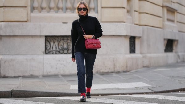 PARIS, FRANCE - DECEMBER 17: Diane Batoukina wears long straight brown hair with a center part, natural makeup with pastel pink lipstick, black sunglasses, a black wool turtleneck sweater, dark blue straight-leg jeans, red ribbed socks, black leather loafers shoes, a red quilted leather Chanel flap bag with chain strap, during a street style fashion photo session, on December 17, 2025 in Paris, France. (Photo by Edward Berthelot/Getty Images)