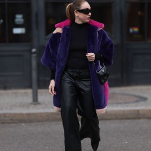 BERLIN, GERMANY - FEBRUARY 08: Sonia Lyson seen wearing & Other Stories black sunglasses, silver earrings, black wool knit high neck sweater, Marina Hoermanseder pink, purple, white, beige fake fur hooded short coat, Marc Cain black leather wide leg pants, Prada Cleo black leather mini bag and Jimmy Choo leather heeled boots, on February 08, 2024 in Berlin, Germany.