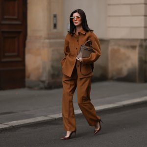 Leo Eberlin is seen wearing half-rimless cat-eye sunglasses with orange lenses and a grey structured top-frame from & Other Stories; a brown two-piece from Arket, consisting of a jacket with dark brown button placket, collar, and large chest pockets, a wide-legged pants with crease; a beige leather “Kelly“ bag from Hermès; and pointed brown leather high heels from Christian Loubouti on October 03, 2024 in Berlin, Germany.