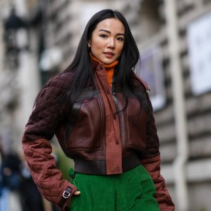 PARIS, FRANCE - MARCH 05: Yoyo Cao wears an orange ribbed wool turtleneck pullover, a brown shiny leather / black leather straps / quilted sleeves zipper jacket, green large ribbed velvet large pants, outside Hermes , during Paris Fashion Week - Womenswear F/W 2022-2023, on March 05, 2022 in Paris, France. (Photo by Edward Berthelot/Getty Images)