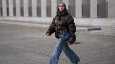 COLOGNE, GERMANY - SEPTEMBER 18: Evi Wave is seen wearing a dark brown high-shine puffer jacket, oversized and voluminous with a high neckline from Oval Square; light blue wide-leg jeans, relaxed fit and slightly washed from Agolde; black square-toe boots with a chunky heel from Vagabond; the Motocross Classic Work, large slouchy blue leather bag with subtle details and seaming from Balenciaga; subtle silver rings from Ariane Ernst; an open blue crocheted beanie-style hat from Kroon02; her brown hair is worn loose on September 18, 2025 in Cologne, Germany. (Photo by Moritz Scholz/Getty Images)