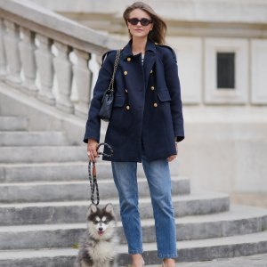 PARIS, FRANCE - MAY 20: Segolene Hyppolite wears sunglasses, a dark navy blue pea coat / peacoat jacket with golden buttons from Tara Jarmon, a black and white top with stripes from Sezane, blue denim pants / jeans from Vanessa Bruno, pointed shoes / pumps from Jonak, a Chanel bag, and holds her husky / dog /pet with a leash, during a street style fashion photo session, on May 20, 2024 in Paris, France. (Photo by Edward Berthelot/Getty Images)