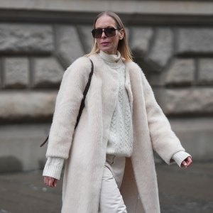 MUNICH, GERMANY - JANUARY 8: Mirja Klein is seen wearing a “Nora brushed wool coat” in a cloud dancer tone with a straight silhouette, clean open front and subtle texture from Marcella London; a cream turtleneck knit sweater with a cable knit pattern, high ribbed collar and fitted cuffs in a cloud dancer shade from Massimo Dutti; off white straight leg Jeans with a high rise and structured cotton fabric from Róhe Frames; a brown belted bucket bag in smooth leather with a structured silhouette and top handle from Le Liffner; oversized rectangular sunglasses with a thin acetate frame, double bridge and tinted lenses from Tom Ford; her long blond straight hair is worn loose and parted in the middle on January 8, 2026 in Munich, Germany. (Photo by Moritz Scholz/Getty Images)