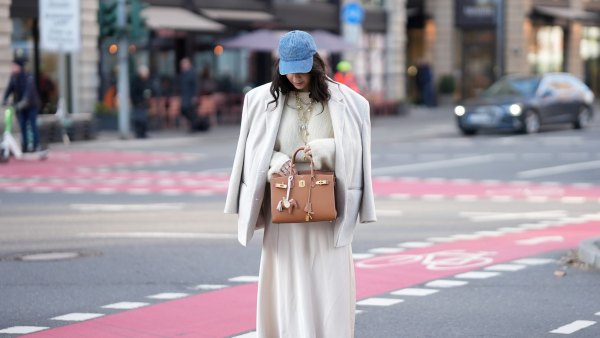 FRANKFURT AM MAIN, GERMANY - JANUARY 20: Cansu Yildirim is seen wearing a cream-coloured satin maxi skirt with flowing, slightly flared silhouette from Philosophy di Lorenzo Serafini; a cloud dancer white fuzzy knit pullover with relaxed fit from H&M tucked in the skirt; a light beige oversized single-breasted wool blazer from ASOS; taupe brown suede leather ankle boots with pointed toe and block heel from Massimo Dutti; a tan brown leather Kelly 25 bag with structured shape and gold hardware from Hermès; a horse-shaped tan brown leather bag charm with light pink strap attached to the bag; a washed blue denim baseball cap from COS; layered golden chain necklaces with pearl pendants; her dark hair is styled in loose waves with a side parting on January 20, 2026 in Frankfurt am Main, Germany. (Photo by Moritz Scholz/Getty Images)