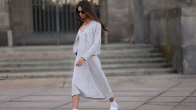 Jill Asemota seen wearing black vintage sunglasses, Dorothee Schumacher grey wool knit long dress, matching Dorothee Schumacher grey wool knit cardigan jacket, white cotton socks, Adidas white leather Samba sneakers, on November 04, 2023 in Berlin, Germany.