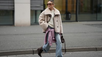 DUESSELDORF, GERMANY - DECEMBER 3: Romina Meier is seen wearing a cropped beige teddy shearling jacket with an oversized collar and contrasting dark brown leather seam detailing from Arket; an off-white fluffy knit pullover from Surprise Paris; a pink and white checkered button-up Borrowed flannel shirt from Our Legacy styled casually tied around her hips; light blue straight-leg jeans with a relaxed fit from Levi’s; dark brown suede pointed-toe heeled boots from Mango; a small sculptural Numéro Neuf leather bag in deep brown sandalwood from Polène; big rectangular shaped brown sunglasses from Vehla; mid-sized hoop earrings from high by honey; her blonde hair is styled in a sleek low bun on December 3, 2025 in Duesseldorf, Germany. (Photo by Moritz Scholz/Getty Images)