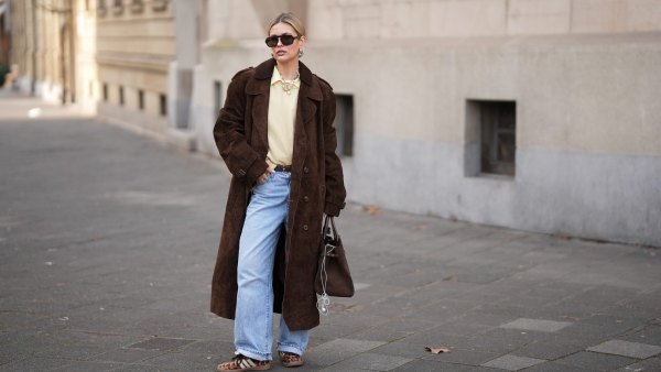 FRANKFURT AM MAIN, GERMANY - JANUARY 21: Julia Kammerer is seen wearing a long chocolate brown suede vintage trench coat with a wide lapel collar, button front and a relaxed fit; a butter yellow blouse with classic collar from JJXX; a light yellow knit sweater from H&M layered above the blouse; light blue wash jeans with turned up cuffs, straight leg and relaxed fit from Levi’s; a mocha brown suede leather Midi Hudson tote bag with top handle and adjustable belt from DeMellier; oversized aviator sunglasses with brown tortoiseshell frames and tinted lenses from H&M; a gold-plated brass necklace with natural freshwater pearls from Scandivv; a golden chain necklace with key lock pendant from MyJewellery; a golden chain necklace with „A“-letter pendant from Scandivv; chunky golden hoop earrings from COS; a slim brown leather belt with golden buckle from Lilysilk; Samba OG leather-trimmed leopard-print pony hair sneakers from Adidas x Wales Bonner; her blonde hair styled back on January 21, 2026 in Frankfurt am Main, Germany. (Photo by Moritz Scholz/Getty Images)