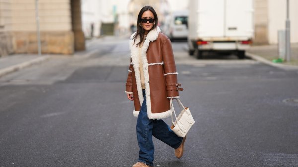 BERLIN, GERMANY - NOVEMBER 25: Laura Noltemeyer is seen wearing a shearling lining coat in a rich cognac tone with an oversized straight silhouette, wide lapels and buckle-strap cuff detailing on the sleeves from Max&Co; layered underneath is a soft beige wool-blend knit sweater with a ribbed crew neckline and ribbed trims from Sézane; dark-blue straight-leg denim trousers with a classic fit from By Aylin Koenig; beige suede winter boots with a rounded toe, exposed stitching and shearling lining from Inuikii; a white structured leather top-handle bag in an intrecciato weave and trapeze silhouette called “Intrecciato Tote” from Bottega Veneta; chunky sculptural gold earrings from Zara; black angular acetate sunglasses with a thick frame and dark lenses from Saint Laurent; her dark-brown hair is worn straight with a center part on November 25, 2025 in Berlin, Germany. (Photo by Moritz Scholz/Getty Images)