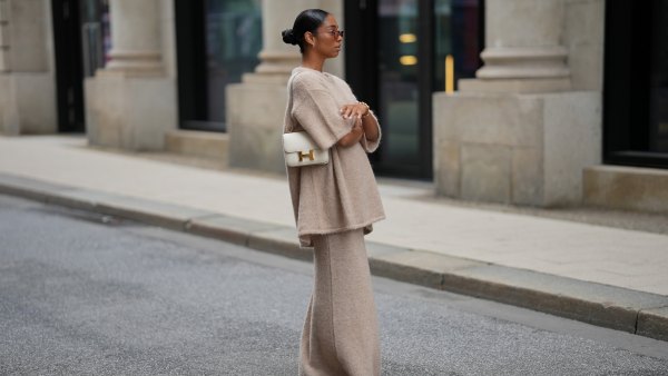HAMBURG, GERMANY - SEPTEMBER 19: Cherifa Akili is seen wearing an oversized beige short-sleeve knit sweater with a soft texture from Byaylinkönig; a matching long knit skirt in a beige tone with subtle seaming at the hem from Byaylinkönig; red pointed-toe heels with a low cut from Prada; The Constance structured white leather shoulder bag with a gold clasp from Hermes; a gold spiral shaped bracelet from Elouise; two gold, metallic rings from Elouise, Wempe; lightly tinted sunglasses in a warm shade COS; her black hair is pulled back in a sleek bun on September 19, 2025 in Hamburg, Germany. (Photo by Moritz Scholz/Getty Images)