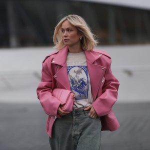 MUNICH, GERMANY - MARCH 06: Nadine Berneis seen wearing The Frankie Shop pink oversized leather jacket, Acne Studios off-white / blue print pattern graphic cotton t-shirt, Acne Studios light blue / grey denim wide leg jeans / pans and Jacquemus pink leather Bambimou bag, on March 06, 2024 in Munich, Germany. (Photo by Jeremy Moeller/Getty Images)